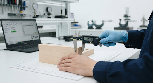 Wooden Tray Component Measurement Wood component being measured with digital calipers during quality inspection