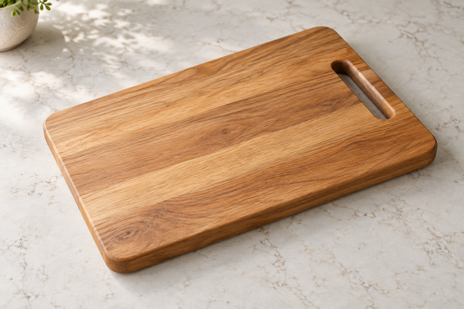 Rectangular hardwood cutting board with a handle opening on a pale stone kitchen worktop