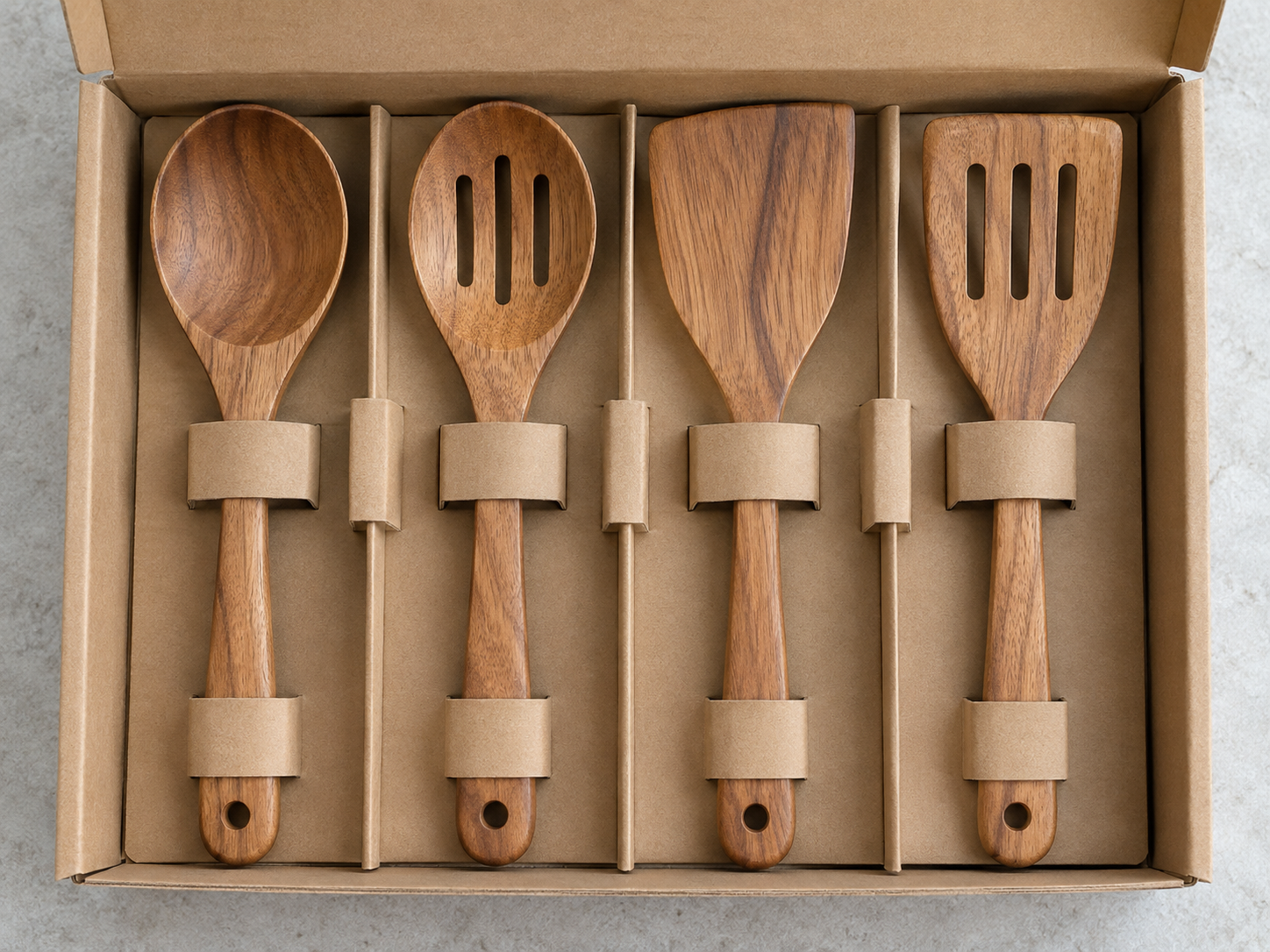Wooden kitchen utensil set in a plain open kraft cardboard box with paper inserts